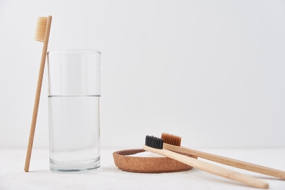 Bamboo toothbrushes baking soda and glass of water on a white background eco friendly toothbrushes