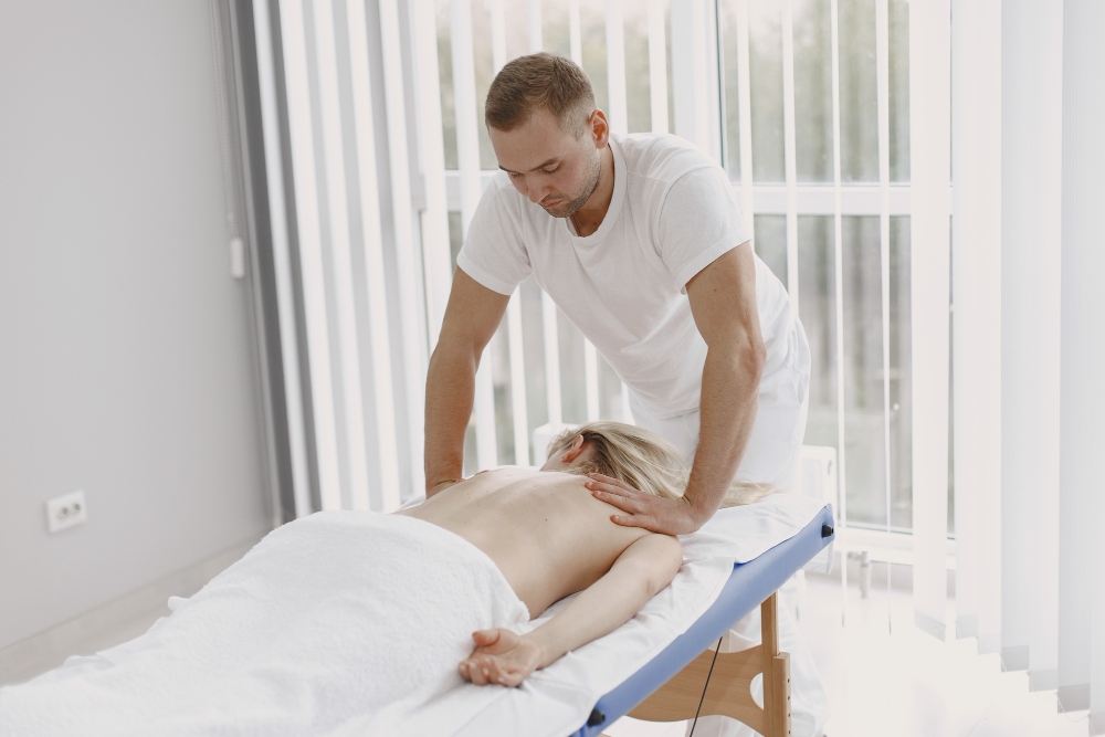 Concept of healthcare and female beauty. Masseuses make a massage of a girl on foldable massage table.