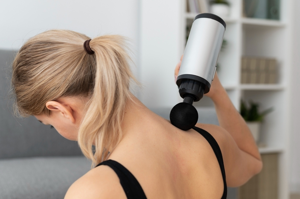 Person using massage gun on shoulder