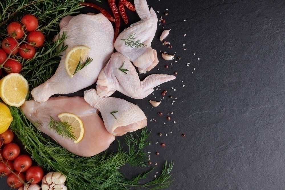 Raw chicken fillet with garlic pepper and rosemary on wooden on chopping board.