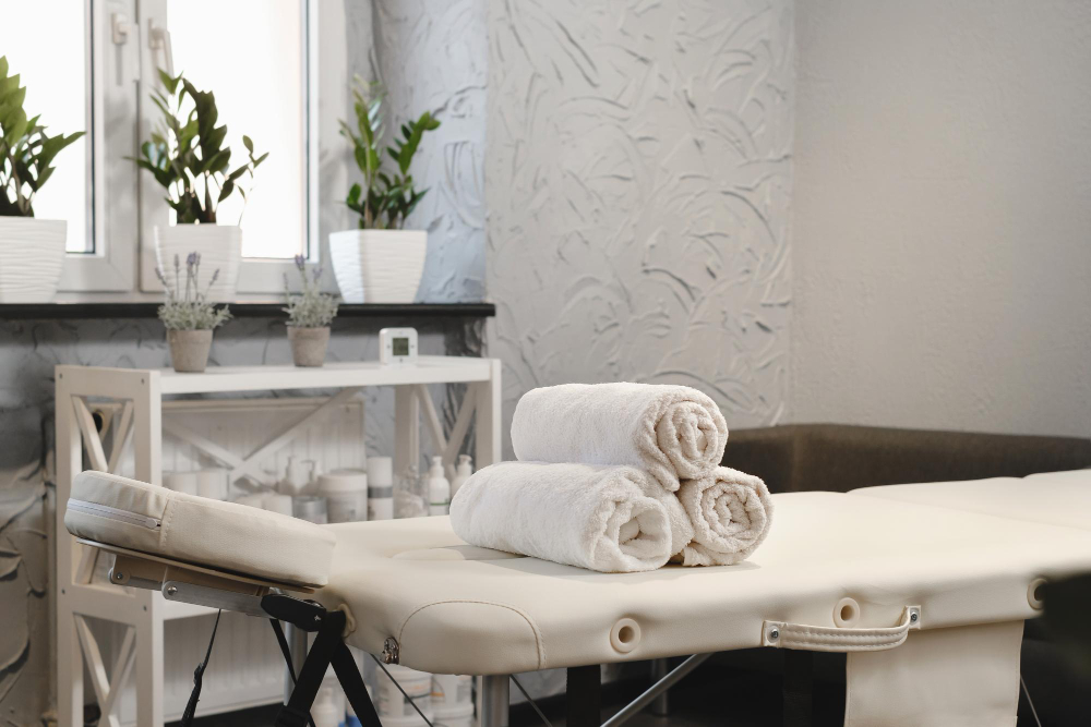 Rolled white towels on massage table in empty salon interior of aesthetic clinic nobody modern