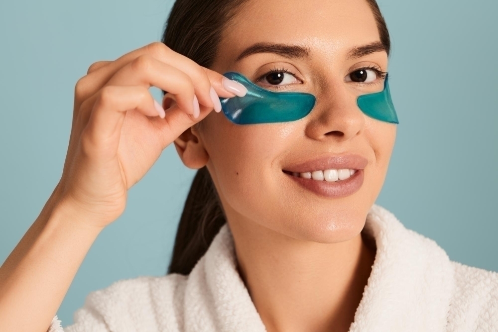 Smiling woman applying gel eye patches