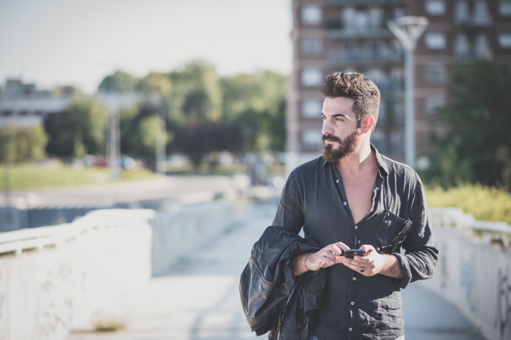 Young handsome attractive bearded model man using smartphone